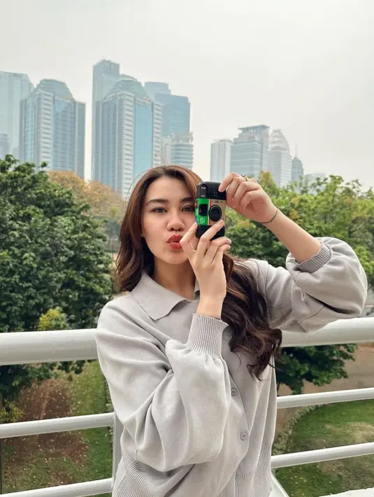 Sambil memegang kamera, Aaliyah Massaid tampil sambil bergaya.