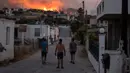 Tiga orang menyaksikan api yang membakar di dekat desa Galataki, dekat Korintus, Yunani, (22/7/2020). Kebakaran musim panas sering terjadi di Yunani, dengan suhu teratur di atas 30 derajat Celcius (86 derajat Fahrenheit). (AP Photo/Petros Giannakouris)