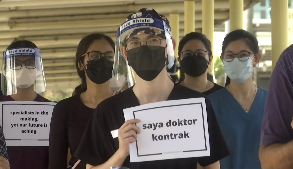 Seorang dokter memegang plakat bertuliskan "Saya seorang dokter kontrak" saat berpartisipasi dalam aksi mogok di Rumah Sakit Sungai Buloh di Selangor, Malaysia, Senin(26/7/2021). Mereka menuntut kondisi yang lebih baik di tengah pandemi virus Corona (COVID-19) yang makin melonjak. (AP Photo)