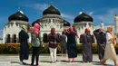 Turis asing dengan mengenakan kerudung mengambil gambar Masjid Agung Baiturrahman di Banda Aceh, Aceh pada 6 Agustus 2019. Selain sebagai tempat ibadah, Masjid Baiturahman juga menjadi tempat wisata bagi turis lokal dan mancanegara. (CHAIDEER MAHYUDDIN / AFP)