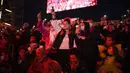 Para penonton karnaval melambaikan ponsel mereka ke udara saat upacara pembukaan Karnaval Nice di Nice, Prancis, 11 Februari 2022. Tema karnaval edisi ke-149 kali ini adalah Raja Hewan. (AP Photo/Daniel Cole)