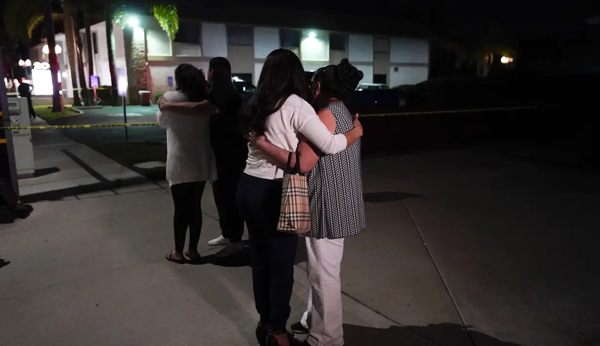 Orang-orang tak dikenal saling menghibur saat mereka berdiri di dekat gedung bisnis tempat penembakan terjadi di Orange, California California (31/3/2021).  Pihak berwenang mengatakan bahwa empat orang, termasuk seorang anak, tewas dalam penembakan tersebut. (AP Photo/Jae C. Hong)