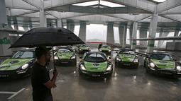 Fotografer saat mengatur armada GrabTaxi yang terdiri dari tujuh mobil mewah untuk pemotretan sebelum beroperasi di Singapura, Selasa (15/9). Mobil-mobil mewah itu akan melayani penumpang secara gratis selama musim balapan F1. (REUTERS/Edgar Su)