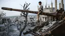 Seorang anak laki-laki Kurdi duduk di atas tank yang hancur di Kota Kobane  yang juga dikenal sebagai Ain al-Arab, Suriah, 26 Maret 2015. (Photo by YASIN AKGUL/AFP)