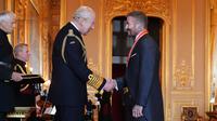 Mantan pesepak bola, David Beckham (kanan) berjabat tangan dengan Raja Inggris, Charles III setelah upacara penobatan gelar Ksatria di Kastil Windsor, Berkshire, Inggris, Selasa (04/11/2025) waktu setempat. (AP Photo/PA/Jonathan Brady)