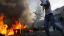 Salah satu pengunjuk rasa mencoba melewati kobaran api yang menutup jalan utama antara Bethlehem dan Hebron pasca terjadi bentrokan dengan militer Israel di Beit Ommar, utara kota Hebron, (25/7/2014). (REUTERS/Mussa Qawasma)