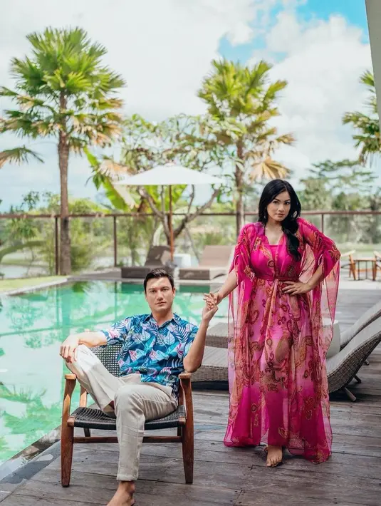 <p>Busana couple dari Titi Kamal dan Christian Sugiono bisa ditiru. Warna berbeda tetap memberi tampilan serasi yang cocok digunakan saat liburan musim panas. [Instagram/titi_kamall]</p>