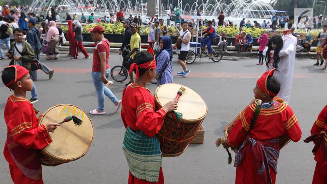 Seniman cilik memainkan alat musik tambur khas Minangkabau saat car free day (CFD) di Jakarta, Minggu (13/1). Pertunjukan ini juga sekaligus untuk mengenalkan keberagaman budaya Nusantara. (Liputan6.com/Angga Yuniar)