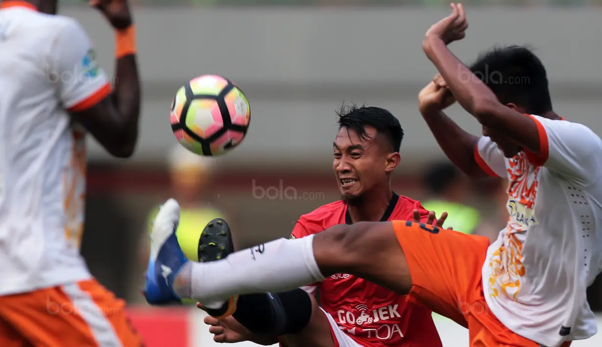 Duel pemain Persija Jakarta, Hargianto (tengah) dan pemain Perseru Serui, Zaenuri (kanan) pada lanjutan Liga 1 2017 di Stadion Patriot Bekasi, Selasa (19/9/2017). Persija menang 1-0. (Bola.com/Nicklas Hanoatubun)