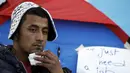 Yosri Adjili (25), seorang pengangguran, melakukan aksi mogok makan dan menjahit mulutnya ketika berunjuk rasa menuntut diberikan pekerjaan, di halaman kantor pemerintah setempat di Kasserine, Tunisia, Rabu (27/1). (REUTERS/Zohra Bensemra)