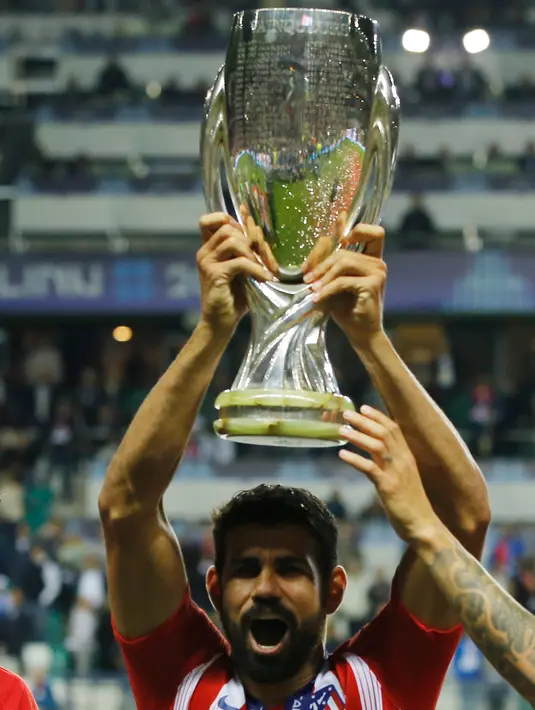 Penyerang Atletico Madrid, Diego Costa mengangkat Piala Super Eropa usai pertandingan melewan Real Madrid di Lillekula Stadium di Tallinn, Estonia, (15/8). Atletico Madrid berhasil mengalahkan Real Madrid dengan skor telak 4-2. (AP Photo/Pavel Golovkin)