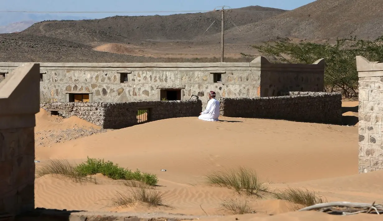 Mantan penduduk Wadi al-Murr, Mohammed al-Ghanbousi berlutut untuk berdoa di gundukan pasir di antara rumah-rumah terlantar di Desa Omani, Wadi al-Murr, Oman, 31 Desember 2020. Penduduk Wadi al-Murr yang sebagian besar mengandalkan pastoral, harus meninggalkan desanya. (MOHAMMED MAHJOUB/AFP)