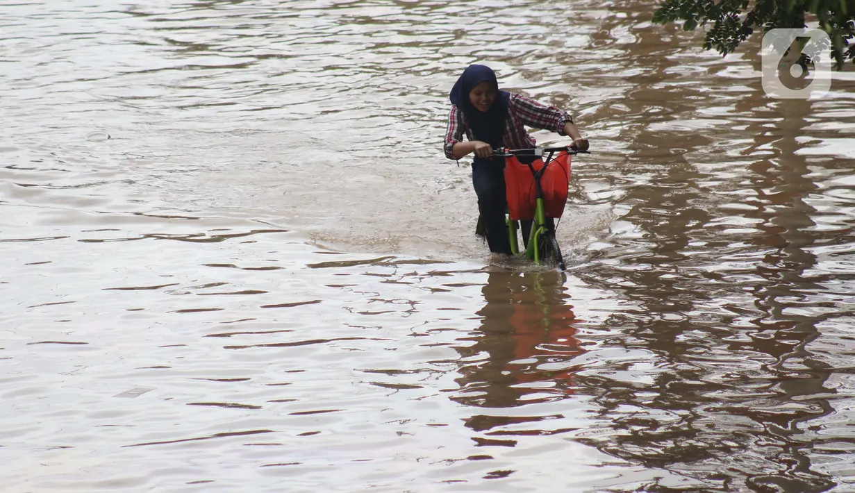 Warga menaiki sepeda menerobos genangan banjir di Jalan Gunung Sahari Jakarta, Selasa (25/2/2020). Hujan yang mengguyur Jakarta sejak Senin (24/2) malam membuat sejumlah kali meluap dan menyebabkan banjir. (Liputan6.com/Helmi Fithriansyah)