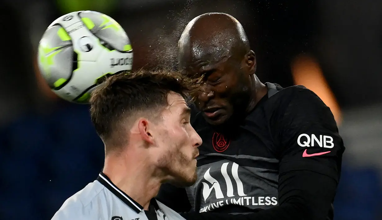 Gelandang Paris Saint-Germain (PSG) Danilo Pereira menyundul bola di depan bek Reims Maxime Busi (kiri) dalam matchday ke-22 Liga Prancis 2021/2022 di Parc des Princes, Senin (24/1/2022) dini hari WIB. PSG menang telak 4-0 atas Reims. (Franck FIFE / AFP)