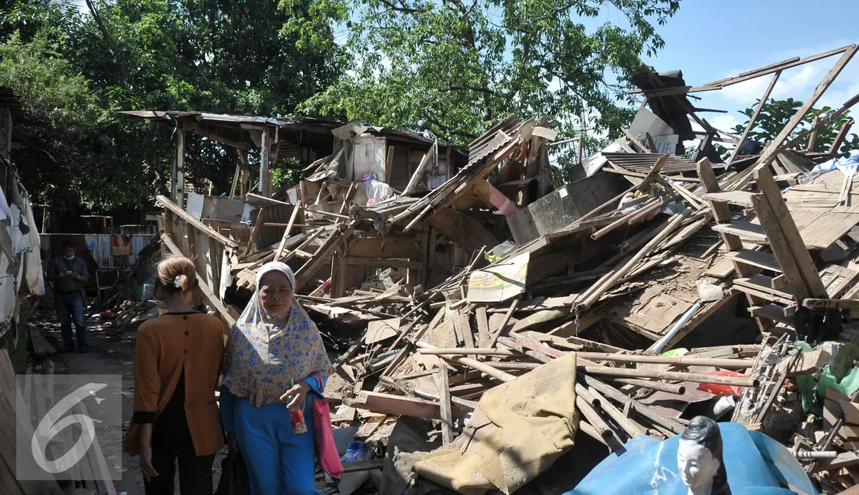 Warga Bukit Duri melintas di pinggir bangunan yang telah dirobohkan Satpol PP, Jakarta, Kamis (29/9). Pemprov DKI lanjutkan pembongkaran belasan rumah di Bukit Duri yang belum sempat dibongkar kemarin. (Liputan6.com/Yoppy Renato)