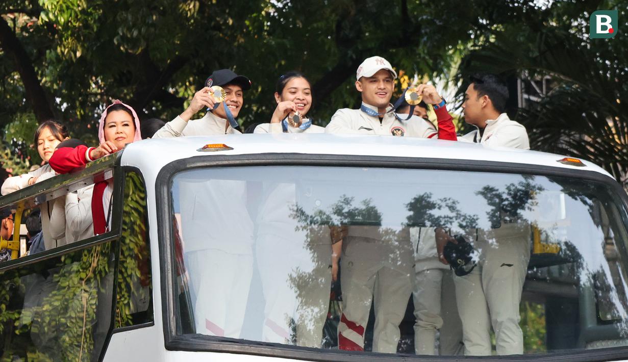 Sejumlah atlet dan ofisial Kontingen Indonesia pada Olimpiade Paris 2024, termasuk peraih medali emas, Veddriq Leonardo dan Rizki Juniansyah serta peraih medali perunggu, Gregoria Mariska Tunjung mengikuti pawai dengan menaiki bus tingkat terbuka Transjakarta menuju Istana Negara, Jakarta Pusat, Kamis (15/8/2024). (Bola.com/Abdul Aziz)