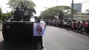 Seorang pengunjuk rasa anti-kudeta dengan poster berdiri di depan kendaraan lapis baja yang dikerahkan di luar gedung Bank Sentral Myanmar di Yangon, Senin (15/2/2021). Pasukan militer Myanmar mulai menerjunkan kendaraan lapis baja di kota-kota besar di Myanmar dan memutus akses internet. (AP Photo)