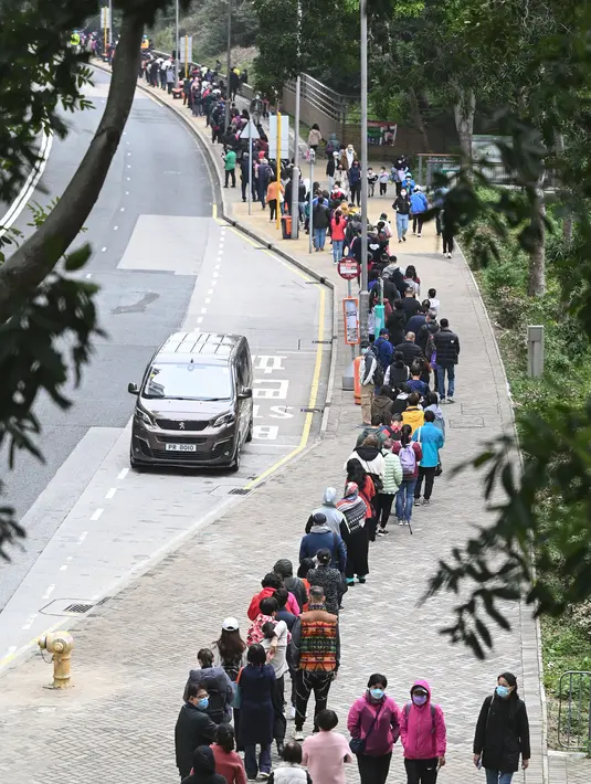 Orang-orang mengantre di stasiun pengumpulan spesimen bergerak untuk pengujian Covid-19 di distrik Tung Chung, Hong Kong pada 10 Februari 2022. Antrean terjadi ketika pihak berwenang bergegas untuk meningkatkan kapasitas pengujian menyusul rekor jumlah infeksi baru yang tinggi. (Peter PARKS / AFP)
