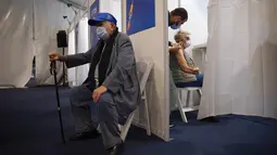 Seorang wanita menerima vaksin virus corona COVID-19 dari staf medis di Pusat Vaksinasi COVID-19, Tel Aviv, Israel, Minggu (3/1/2021). Capaian vaksinasi di Israel merupakan yang tertinggi di dunia untuk saat ini. (AP Photo/Oded Balilty)