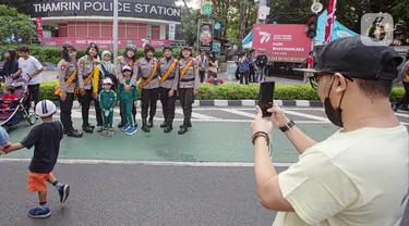 Sejumlah anak berfoto dengan polisi wanita (Polwan) saat Car Free Day (CFD) di Bundaran HI, Jakarta, Minggu (2/7/2023). Masih dalam nuansa memperingati HUT ke-77 Bhayangkara, kehadiran Polwan saat CFD menyita perhatian warga untuk berswafoto. (Liputan6.com/Faizal Fanani)