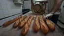 Baker David Buelens memasukkan baguette ke dalam keranjang di sebuah toko roti, di Versailles, sebelah barat Paris, Selasa, 29 November 2022.Industri roti Prancis telah berkampanye selama beberapa tahun untuk mendapatkan status ini dalam Daftar Perwakilan Warisan Budaya Takbenda Kemanusiaan. (AP Photo/Michel Euler)