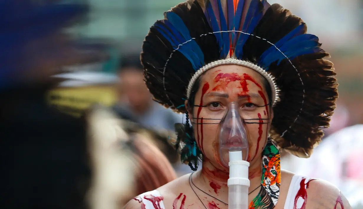 Seorang perempuan Brasil mengenakan masker oksigen portabel dalam aksi unjuk rasa menuntut keadilan iklim dan menentang kebakaran hutan yang melanda seluruh negeri di Sao Paulo, Brasil, pada tanggal 22 September 2024. (Miguel SCHINCARIOL/AFP)