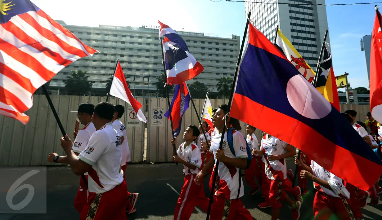 Sejumlah remaja membawa bendera negara-negara peserta Sea Games di Jakarta, Minggu (30/4). Kirab itu berlangsung guna menyambut Sea Games Kuala Lumpur 2017. (Liputan6.com/Johan Tallo)