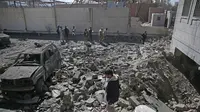 Sejumlah warga mengamati reruntuhan pusat penahanan Houthi yang diserang pasukan koalisi Saudi dari udara di Sanaa (13/12/2017). (AP Photo/Hani Mohammed)