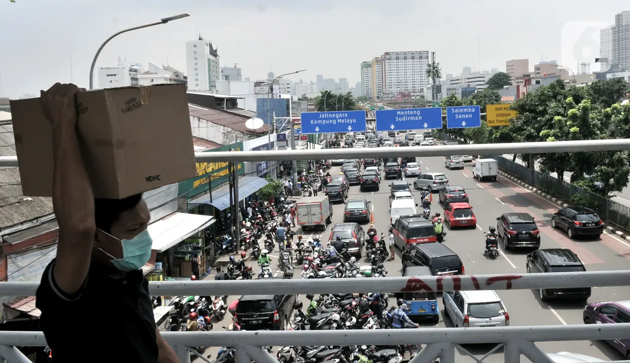 Warga membawa kardus berisi masker yang dibeli di Pasar Pramuka, Jakarta, Senin (16/3/2020). Pasar Pramuka diserbu pembeli yang mencari masker guna mengantisipasi virus Corona, membuat sebagian badan jalan dimanfaatkan sebagai parkiran sehingga menyebabkan kemacetan. (merdeka.com/Iqbal Nugroho)