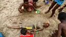 Anak-anak mengubur teman mereka di pasir saat mereka bermain di pantai Cabourg, barat laut (18/8/2021). Acara ini sebagai bagian dari kampanye "Lupa Liburan" yang diselenggarakan oleh LSM Prancis Secours Populaire untuk anak-anak yang keluarganya tidak mampu pergi berlibur. (AFP/Sameer Al-Doumy)