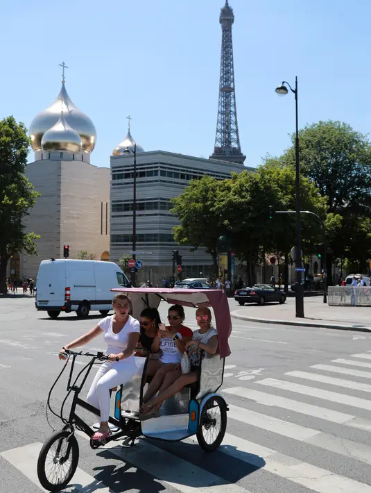 Wisatawan berkeliling kota Paris menggunakan transportasi becak, Prancis, (7/7). Desain becak di Paris ini memiliki posisi penarik becak dibagian depan berbeda dengan becak yang ada di Indonesia. (AFP Photo/Jacques Demarthon)