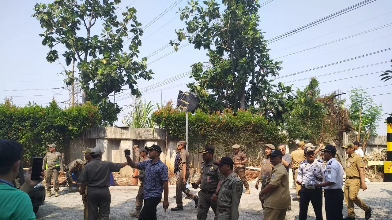 Satpol PP Jakarta Utara membongkar pagar pembatas Jalan Pantai Indah Timur, Jakarta Utara dengan Perumahan Pinisi Pantai Indah Kapuk, Jakarta Utara. (Istimewa)