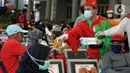 Petugas KAI yang mengenakan kostum Natal membagikan masker kepada calon penumpang di Stasiun Senen, Jakarta, Jumat (25/12/2020). Pembagian ini dilakukan untuk mengganti masker yang sudah dipakai calon penumpang selama perjalanan. (merdeka.com/Imam Buhori)