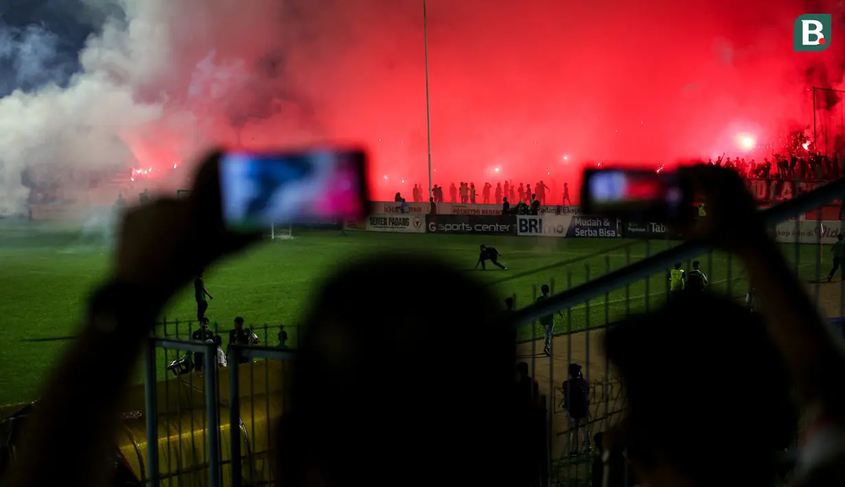 <p>Para suporter menyalakan flare yang membuat laga leg kedua final Pegadaian Liga 2 2023/2024 dihentikan untuk keunggulan PSBS Biak 3-0 atas Semen Padang di Stadion GOR Haji Agus Salim, Padang, Sabtu (9/3/2024). (Bola.com/Bagaskara Lazuardi)</p>