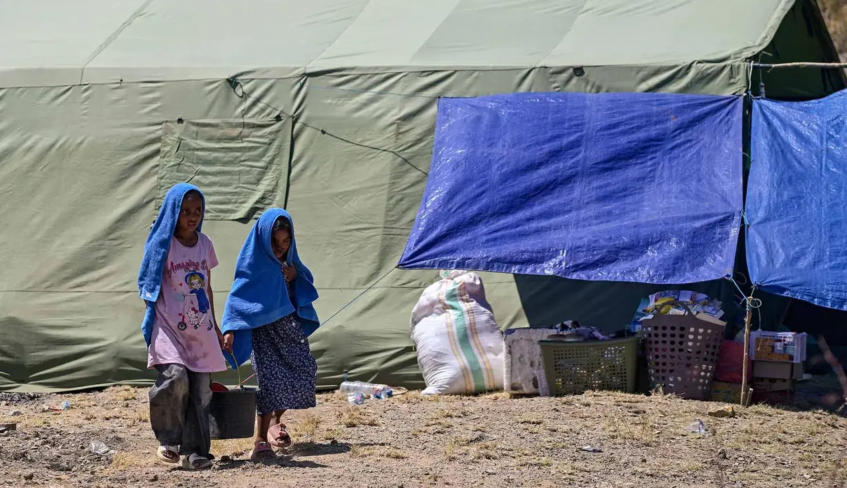 Warga membawa ember berisi air bersih di dekat sebuah tenda di lapangan terbuka di Marapokot, Nagekeo, Nusa Tenggara Timur, Senin, 17 Agustus 2026, (AFP/ Juni Kriswanto)