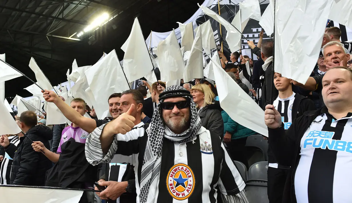 Penggemar Newcastle United mengibarkan bendera hitam putih dan spanduk untuk merayakan pengambilalihan klub oleh konsorsium yang dipimpin Pangeran Arab Saudi selama pertandingan antara Newcastle United dan Tottenham Hotspur di St James' Park, Minggu (17/10/2021). (AFP/Paul Ellis)