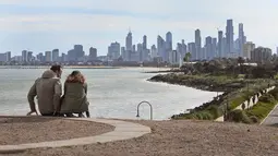 Suami istri beristirahat dari berolahraga dengan pemandangan cakrawala Melbourne (11/8/2020). Negara bagian Victoria melaporkan 19 kematian akibat virus corona pada 11 Agustus, menjadikannya hari yang sama mematikan bagi pandemi di negara itu meskipun jumlah kasus baru turun. (AFP/William West)