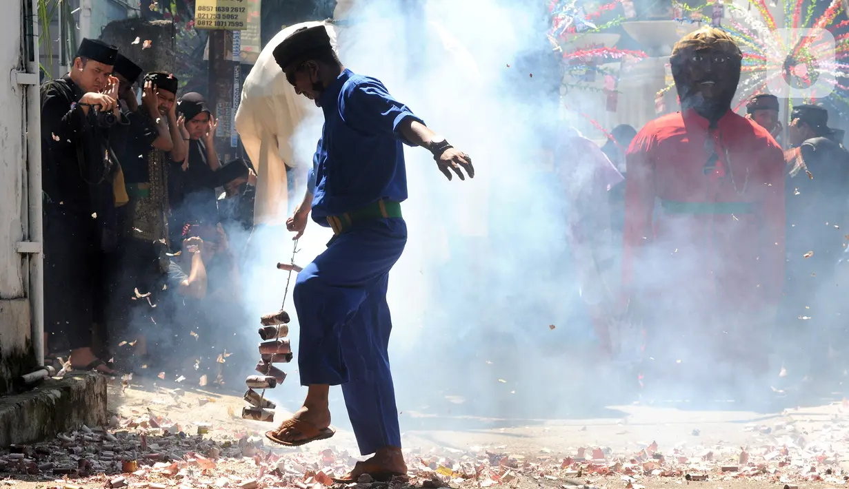 Warga memegang petasan besar yang dibakar saat kegiatan pawai jelang Ramadan di kawasan Pondok Cabe Ilir, Tangerang Selatan, Banten, Minggu (27/3/2022). Kegiatan ini dalam rangka mengajak kaum muslim untuk melakukan ibadah puasa satu bulan penuh saat Ramadan. (merdeka.com/Arie Basuki)