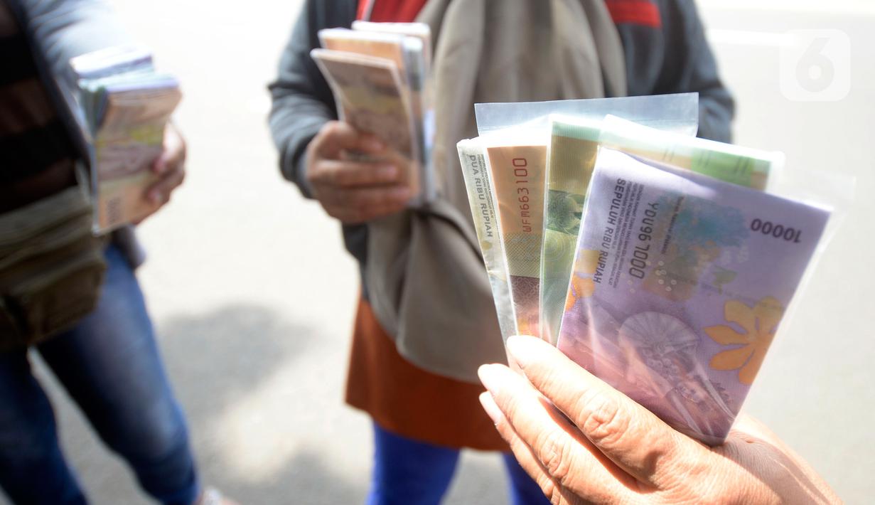 Penjual jasa penukaran uang menawarkan uang baru berbagai pecahan kepada pengguna jalan di kawasan Bintaro Sektor 2, Jakarta Selatan, Selasa (12/05/2020). Pembeli uang kertas baru yang biasanya ramai menjelang Lebaran, kini sepi di tengah pandemi virus corona Covid-19. (merdeka.com/Dwi Narwoko)