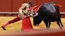 Matador asal Spanyol, Julian "El Juli" Lopez melakukan operan dengan muleta-nya saat bertarung dengan banteng di arena adu banteng Real Maestranza di Sevilla, Spanyol (21/4). (AFP Photo/Cristina Quicler)