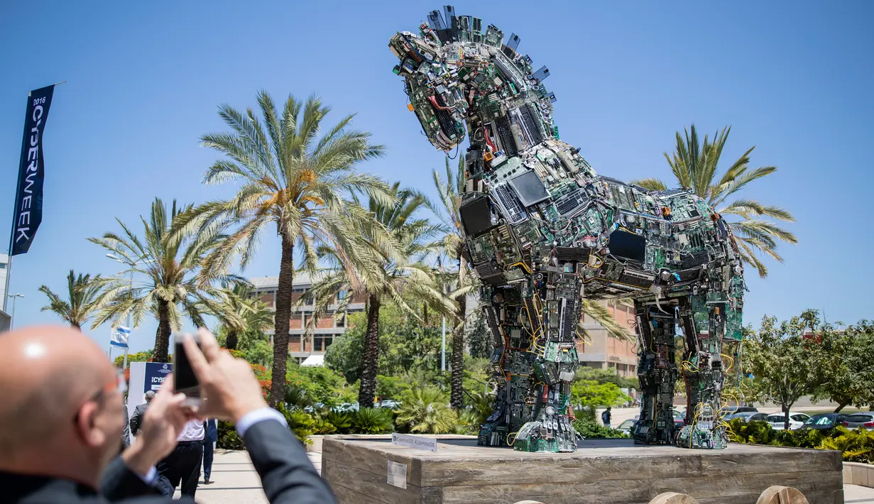 Seorang pria mengambil gambar patung kuda troya bernama "Cyber Horse" yang terbuat dari ribuan komputer dan komponen ponsel yang terinfeksi virus, di pintu masuk konferensi Cyber Week tahunan di Tel Aviv University, Israel, Senin (20/6). (Jack GUEZ/AFP)