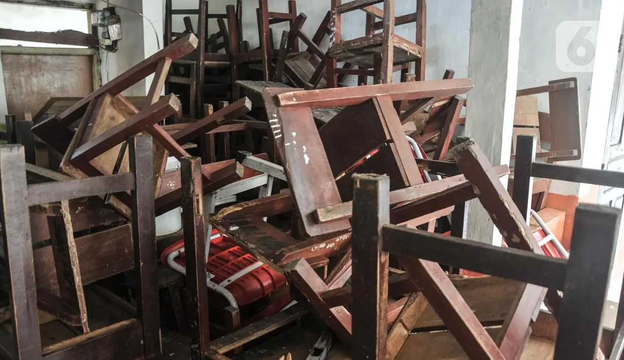 Tumpukkan bangku sekolah yang dipindahkan dari ruang kelas yang rusak di SDN Pancoranmas 3, Depok, Jawa Barat, Minggu (24/7/2022). Selain ruang kelas, perpustakaan dan ruangan untuk penjaga sekolah pun telah lebih dulu rusak. (merdeka.com/Iqbal S. Nugroho)