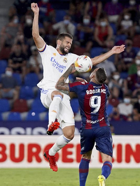 Pemain Real Madrid Nacho (kiri) berebut bola dengan pemain Levante Roger Marti pada pertandingan La Liga Spanyol di Stadion Ciutat de Valencia, Valencia, Spanyol, Minggu (22/8/2021). Pertandingan berakhir dengan skor 3-3. (AP Photo/Alberto Saiz)