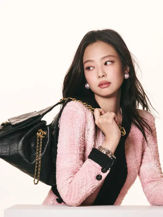 Dalam pemotretan yang dilakukan oleh David Sims, Jennie tampil dengan gaya effortless chic yang menjadi ciri khasnya. Mengenakan jaket tweed berwarna pink pastel dengan detail hitam, ia memadukannya dengan perhiasan sederhana yang tetap memancarkan kemewahan.  [Dok/CHANEL].
