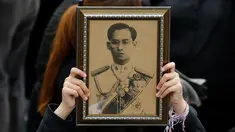 Seorang pelayat wanita memegang foto Raja Bhumibol Adulyadej saat berkumpul di luar Grand Palace sambil menyanyikan rekaman lagu kerajaan untuk menghormati raja mereka, di Bangkok, Thailand, (22/10) (REUTERS/Jorge Silva)