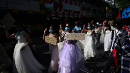 Sejumlah wanita Myanmar memakai gaun pengantin memegang plakat selama demonstrasi menentang kudeta militer 1 Februari di Yangon (10/2/2021).  Militer Myanmar melakukan kudeta pada 1 Februari dan menahan sejumlah tokoh termasuk Aung San Suu Kyi. (AFP/ Ye Aung Thu)