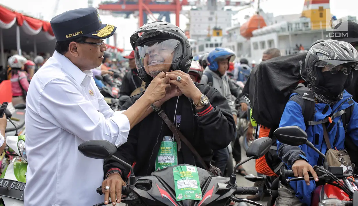 Menhub Budi Karya Sumadi memasangkan helm peserta mudik gratis sepeda motor saat menyambut kedatangan mereka di Pelabuhan Tanjung Priok, Rabu (20/6). Ada 699 sepeda motor dan 1.650 penumpang kembali ke Jakarta dari Semarang. (Liputan6.com/Faizal Fanani)