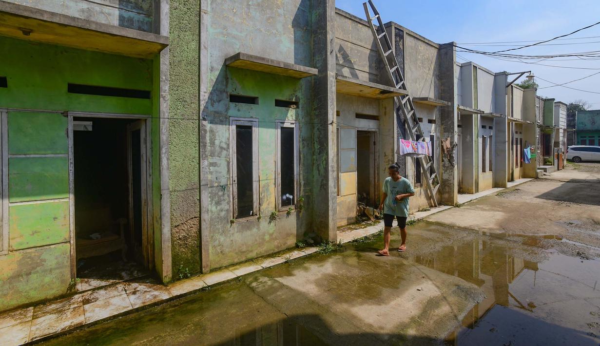 Warga melangkah melewati rumah nan ditinggal pergi pemiliknya akibat kerapkali banjir lantaran luapan Pesanggrahan nan alirannya menyempit lantaran longsoran sampah dari Tempat Pembuangan Akhir (TPA) Cipayung di Perumahan Griya Alif, Sawangan, Depok, Jawa Barat, Kamis (14/5/2026). (merdeka.com/Arie Basuki)