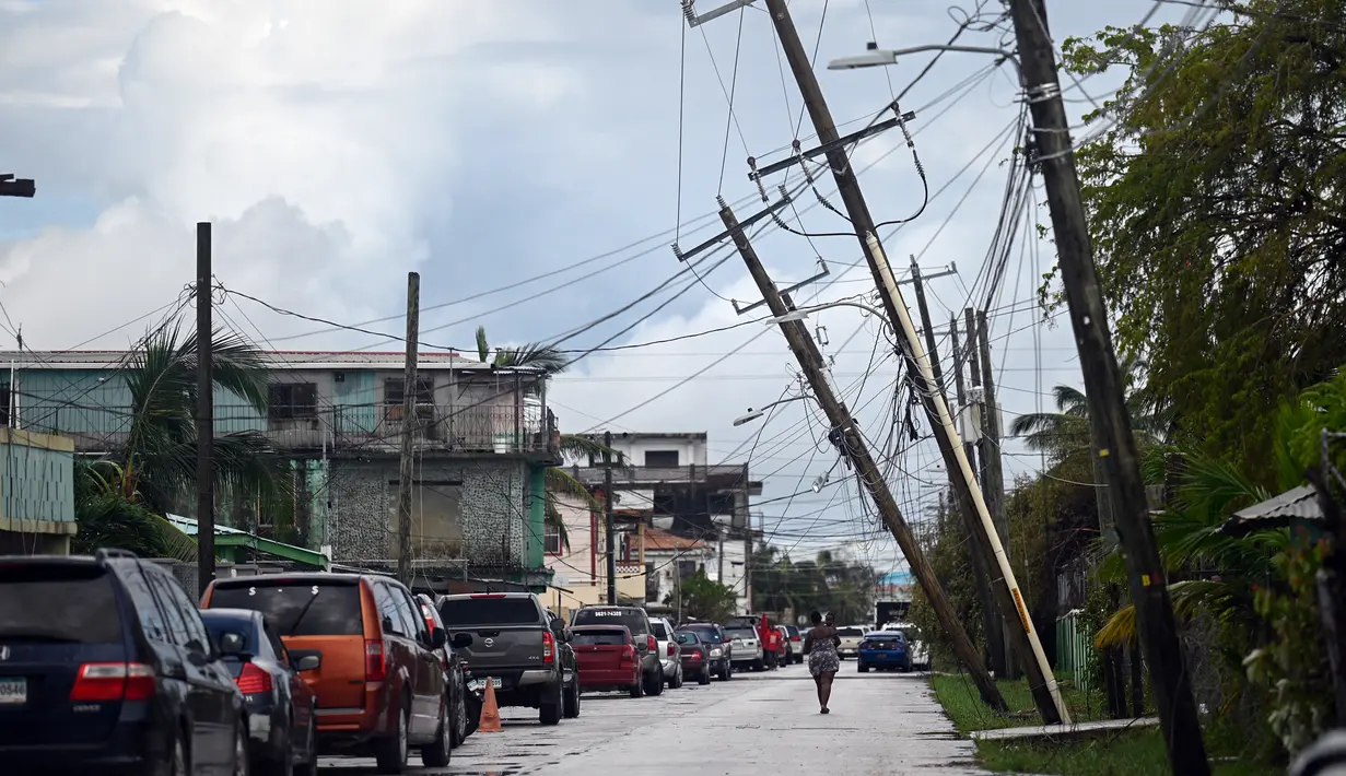 Seorang wanita berjalan melalui jalan setelah Badai Lisa di Belize City, Belize, 3 November 2022. Badai Tropis Lisa menyebabkan banjir dan membuat sebagian negara itu menjadi gelap gulita. (Johan ORDONEZ/AFP)