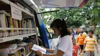 Seorang warga membaca di mobil perpustakaan keliling di Kelurahan Pocanan, Kediri, Jawa Timur. (Antara)